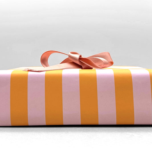 wide classic stripe wrapping paper in orange and pink by Heather Evelyn. Wrapped with a pink ribbon bow