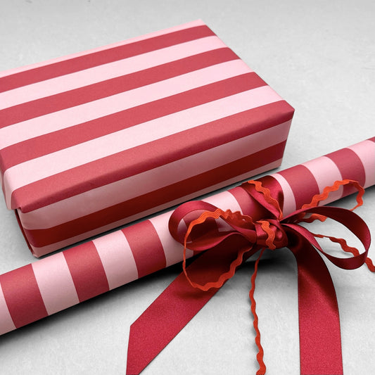 wide classic stripe wrapping paper in red and pink by Heather Evelyn, pictured gift wrapped with red bow and rik rac