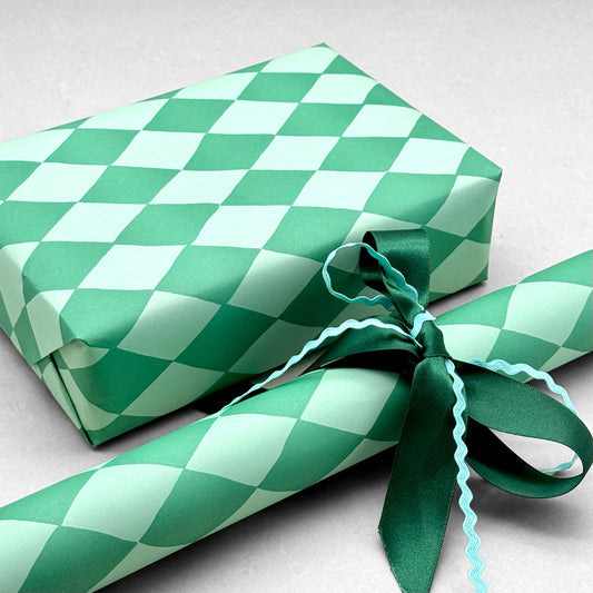 a sheet of wrapping paper with a two tone green large diamond pattern. By Heather Evelyn and shown wrapped as a gift