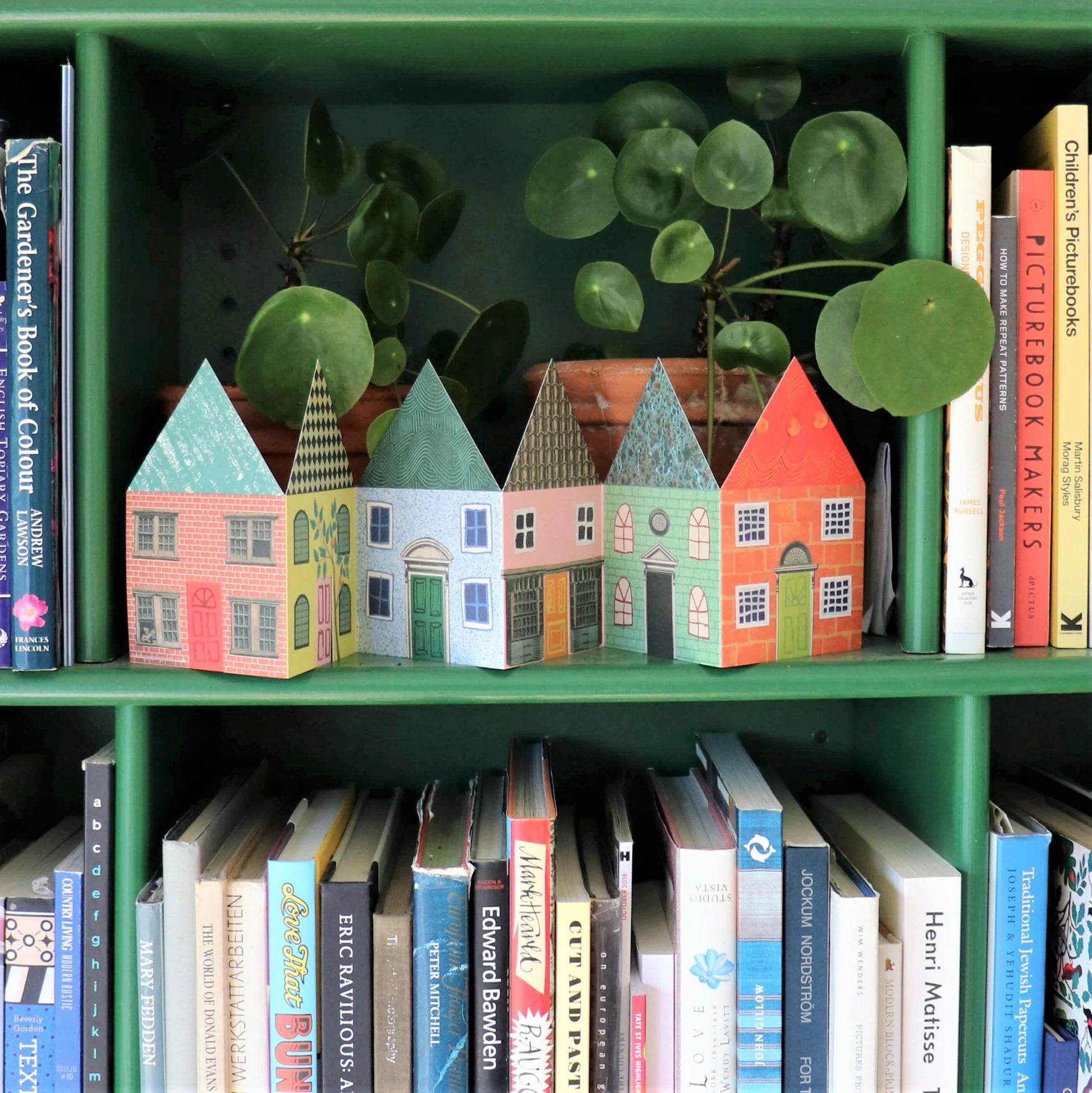 a concertina greetings card of six colourful houses by Hadley Paper Goods, shown on a green shelf