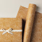 a sheet of wrapping paper in mustard with a small abstract pattern in white