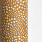 a sheet of wrapping paper in mustard with a small abstract pattern in white