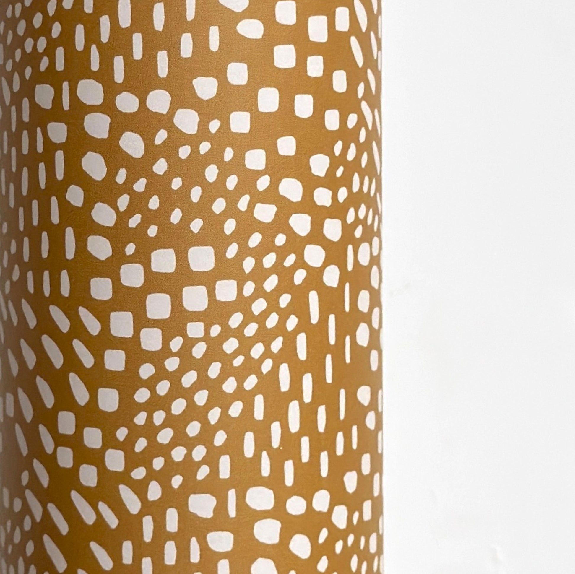 a sheet of wrapping paper in mustard with a small abstract pattern in white