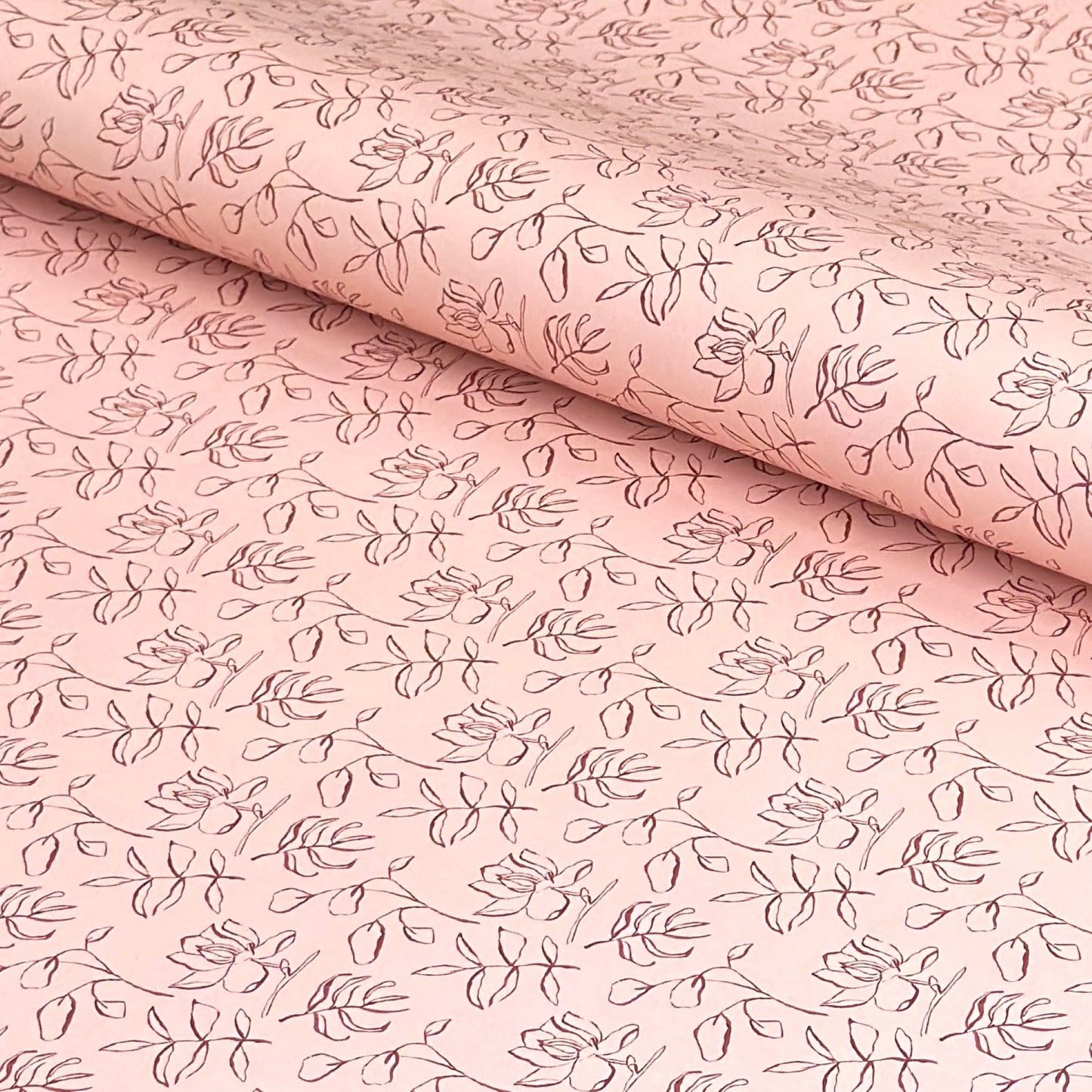 a sheet of wrapping paper in blush pink with a floral sketched pattern in brown