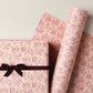 a sheet of wrapping paper in blush pink with a floral sketched pattern in brown