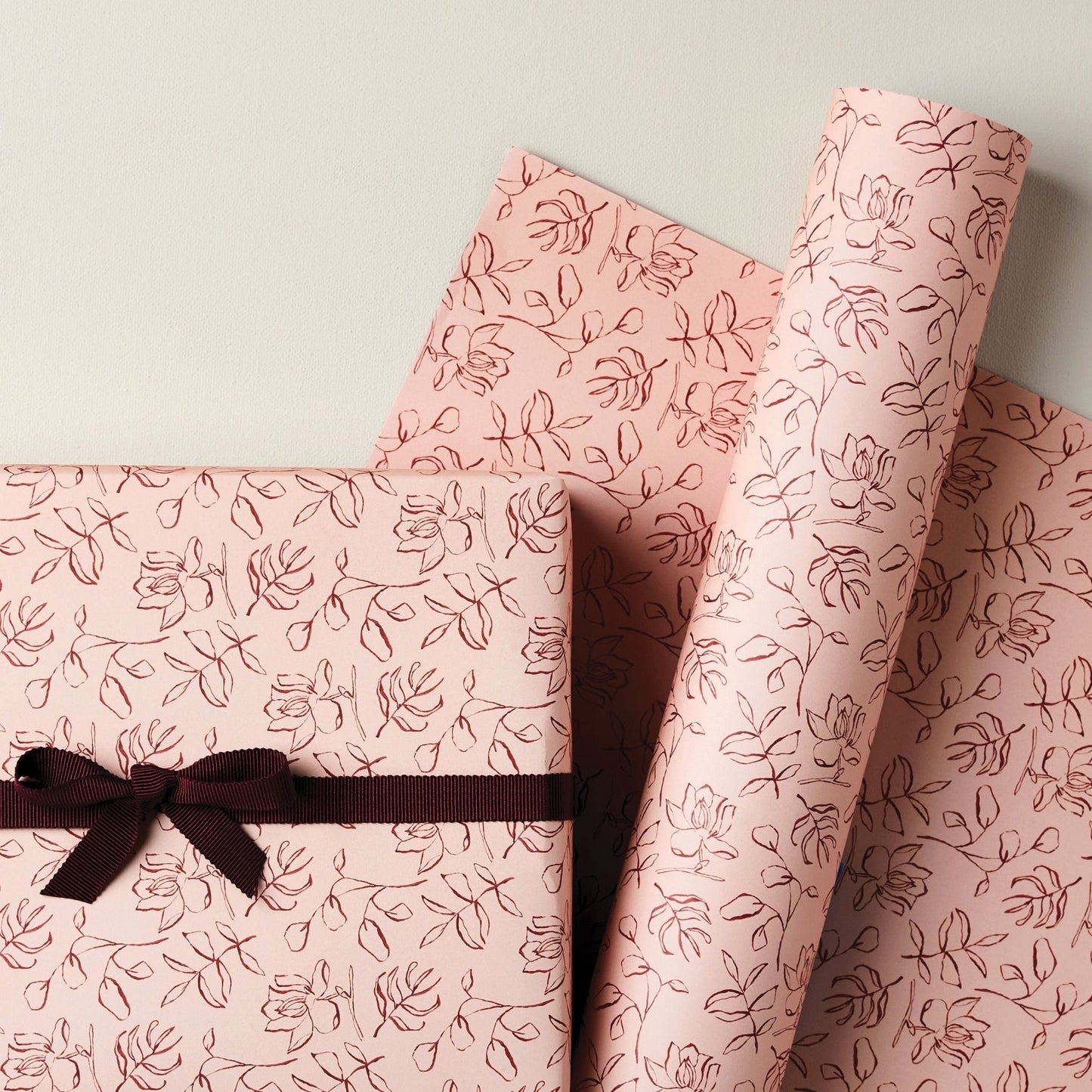 a sheet of wrapping paper in blush pink with a floral sketched pattern in brown