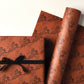 a sheet of brown wrapping paper with an abstract floral pattern in black