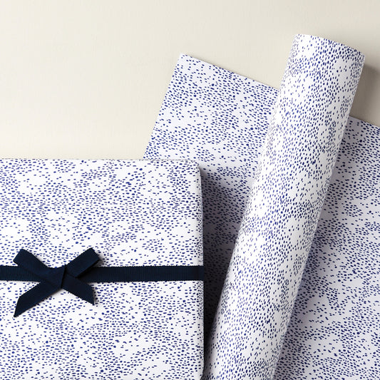 a sheet of wrapping paper in white with a blue speckle design