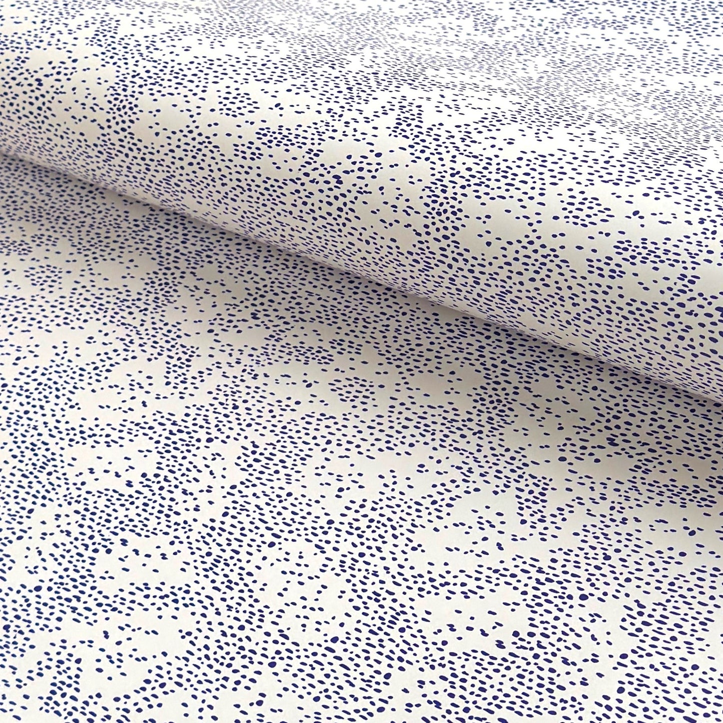 a sheet of wrapping paper in white with a blue speckle design