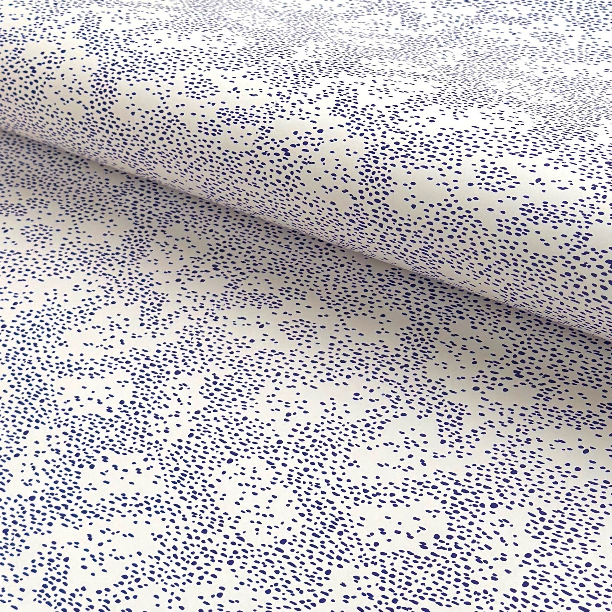 a sheet of wrapping paper in white with a blue speckle design