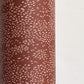 a sheet of wrapping paper in rust with an abstract pink speckled design