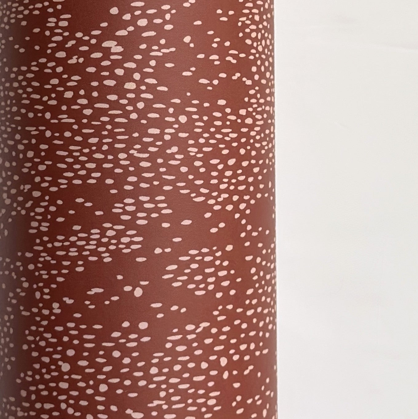 a sheet of wrapping paper in rust with an abstract pink speckled design