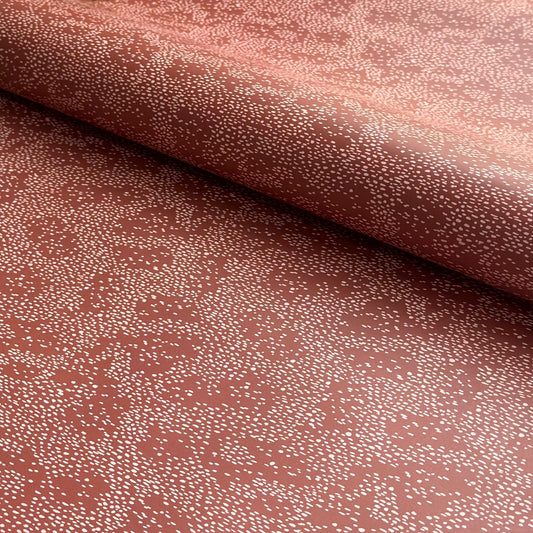 a sheet of wrapping paper in rust with an abstract pink speckled design