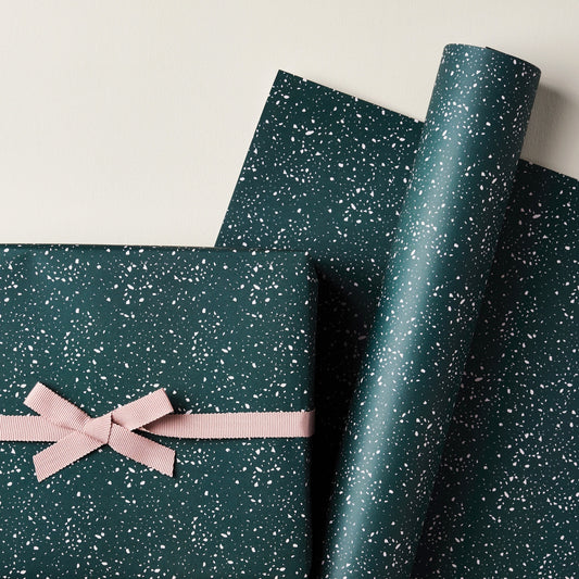 a sheet of wrapping paper in dark green with a speckle design in white