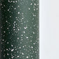 a sheet of wrapping paper in dark green with a speckle design in white