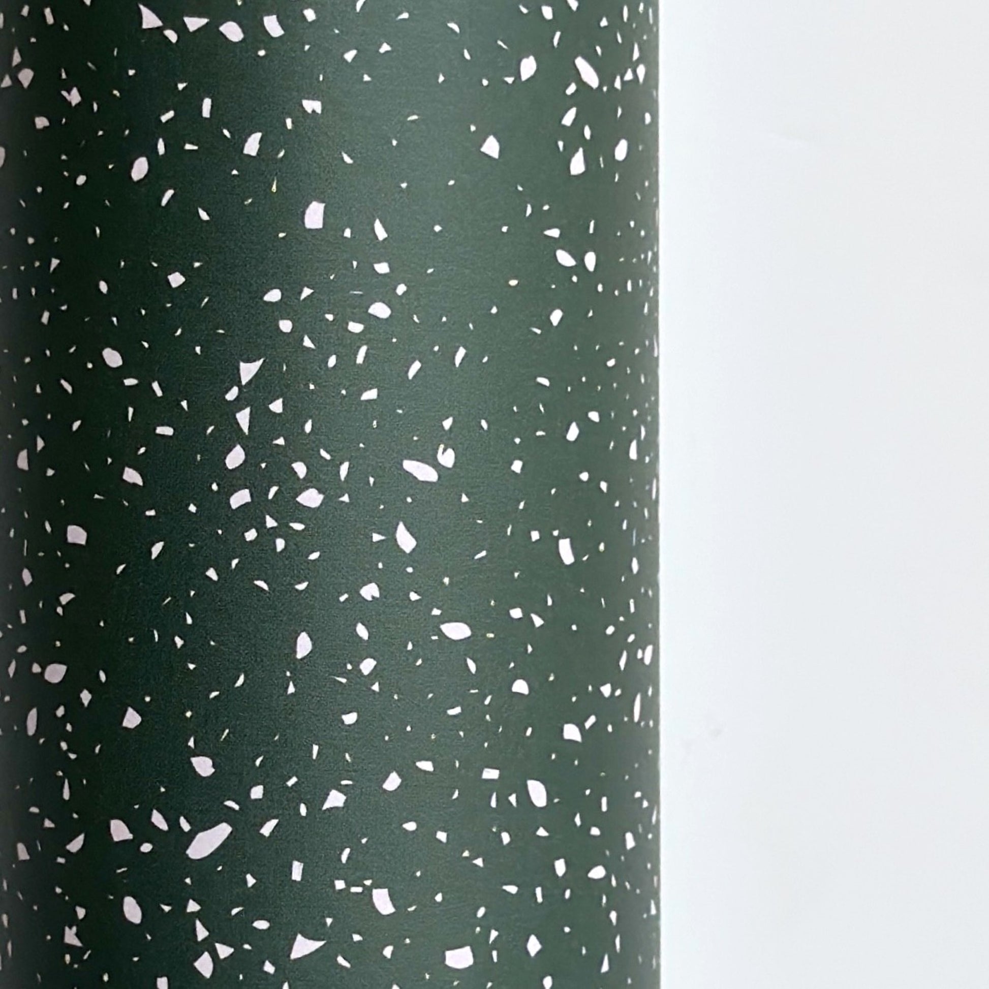 a sheet of wrapping paper in dark green with a speckle design in white