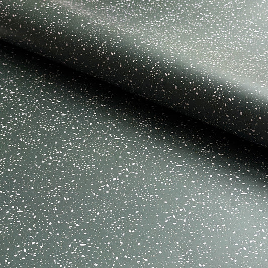 a sheet of wrapping paper in dark green with a speckle design in white