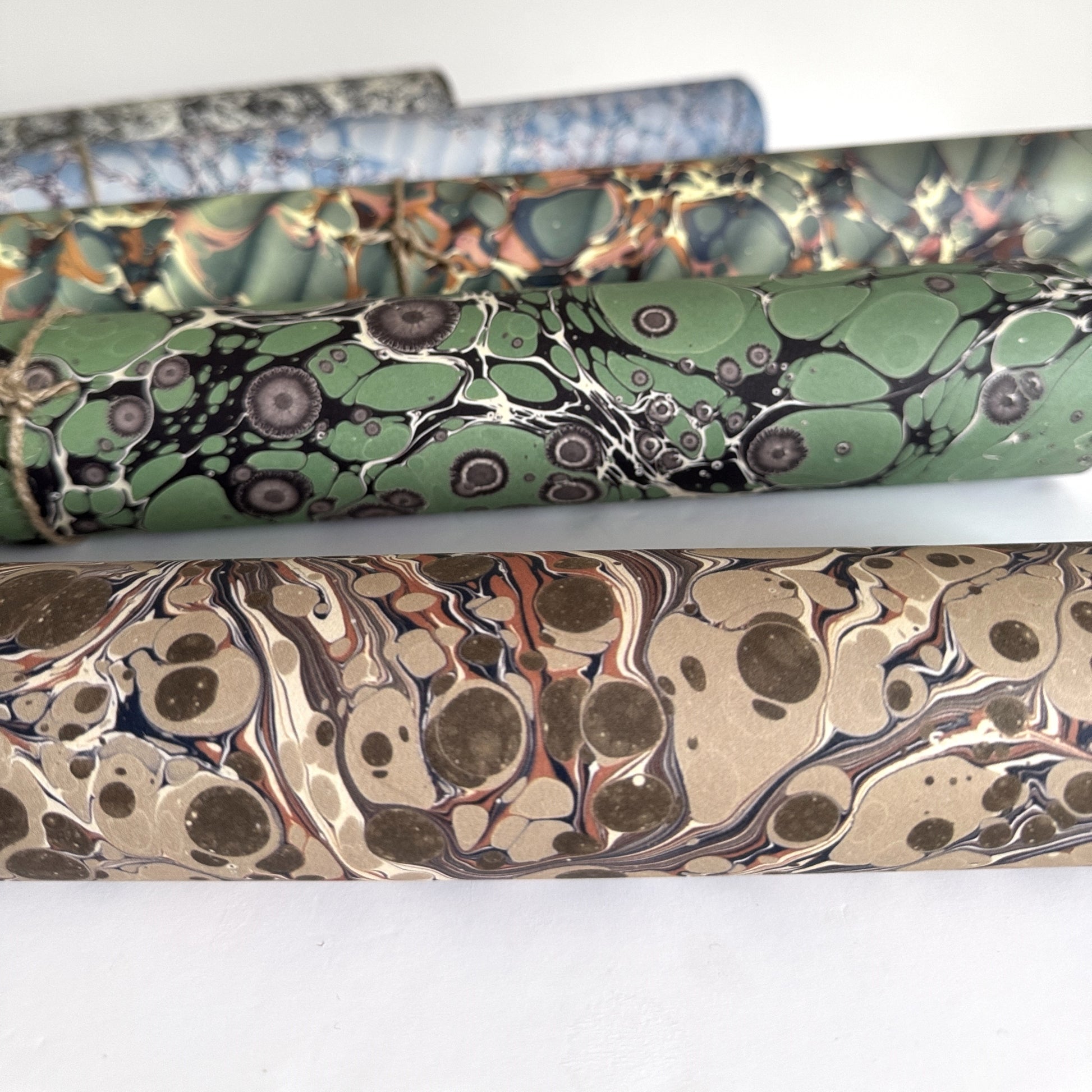 sheet of printed marbled wrapping paper by Jemma Lewis, stone effect in taupe, blush pink and beige. Pictured rolled