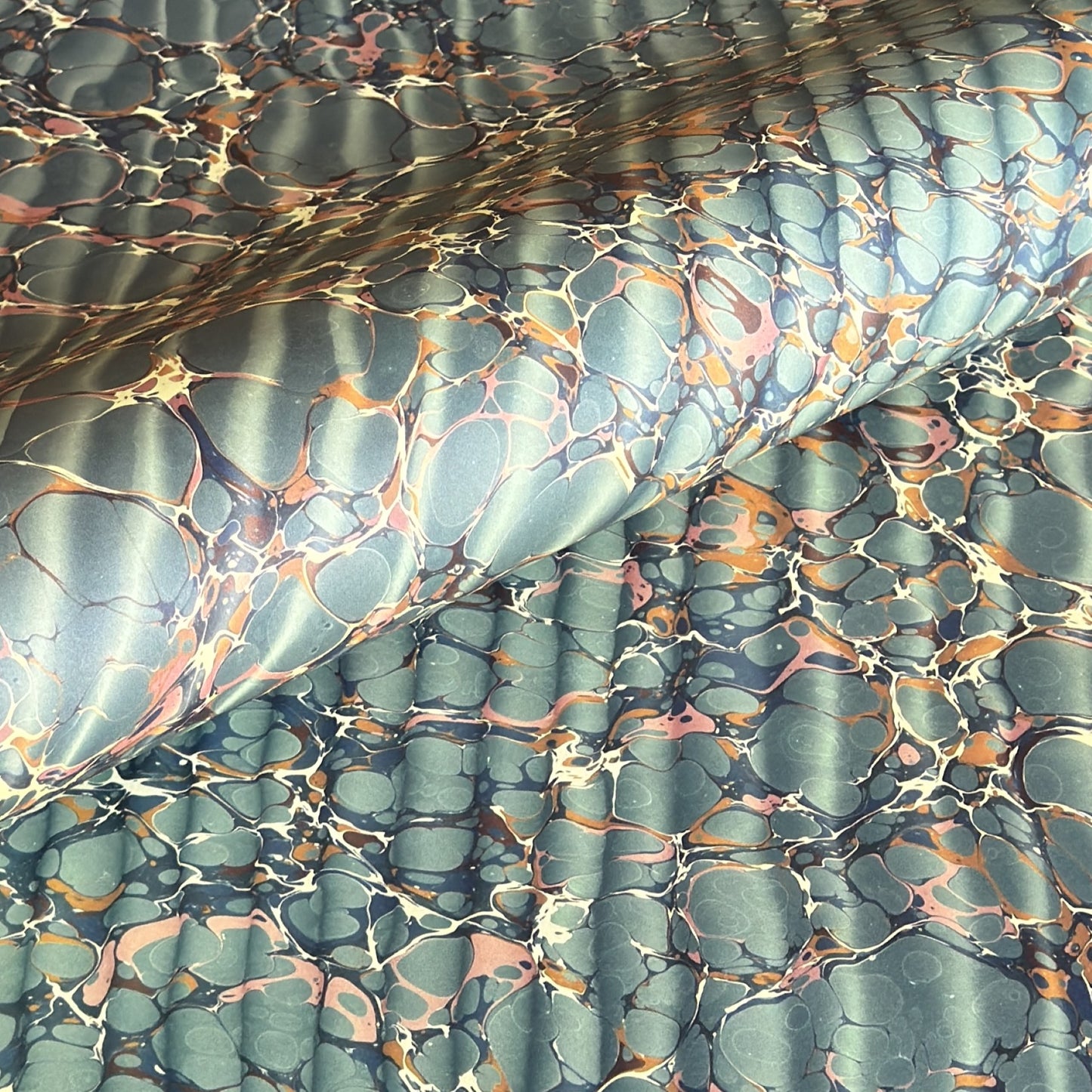 sheet of printed marbled wrapping paper by Jemma Lewis, ripple effect in teal green, ochre and pink