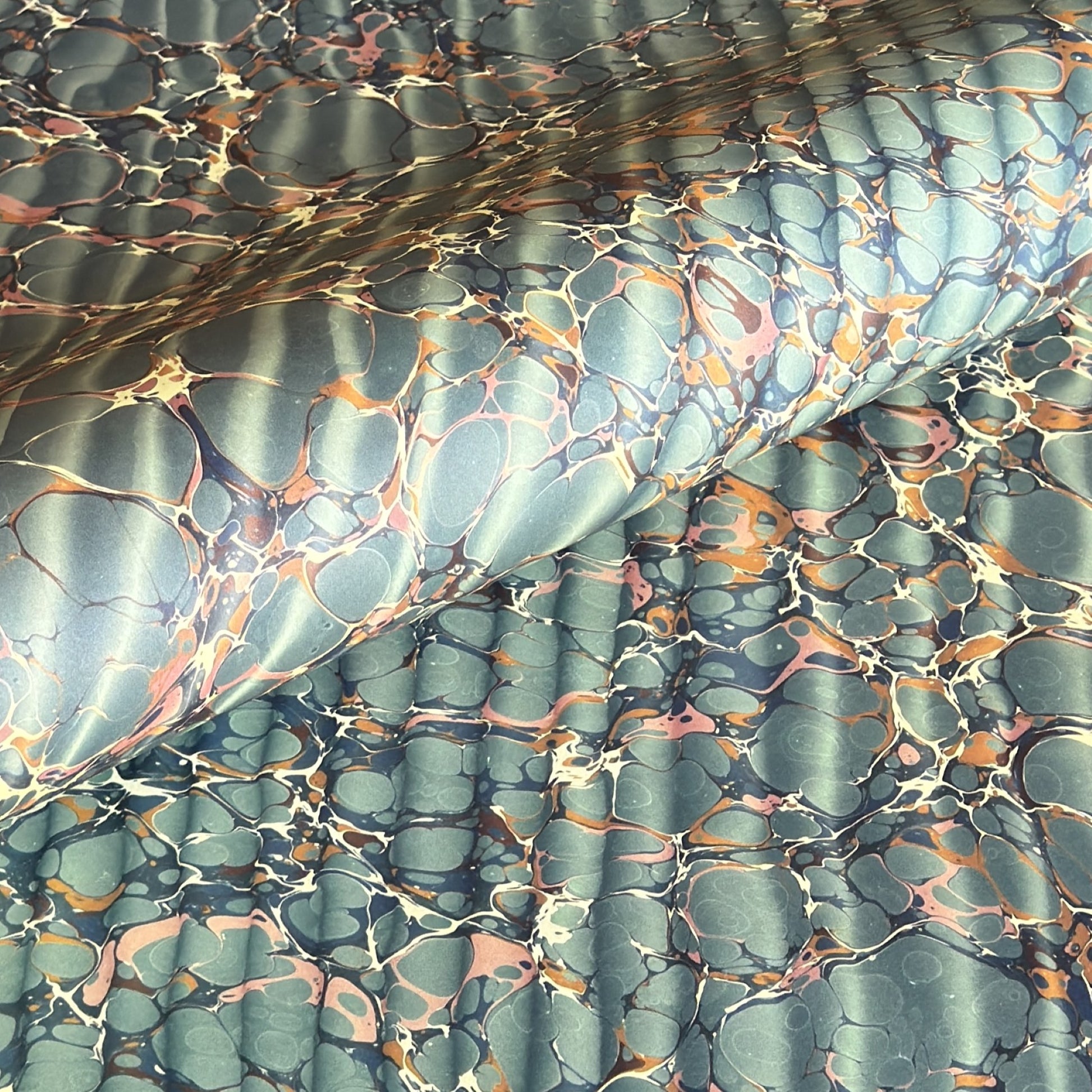 sheet of printed marbled wrapping paper by Jemma Lewis, ripple effect in teal green, ochre and pink