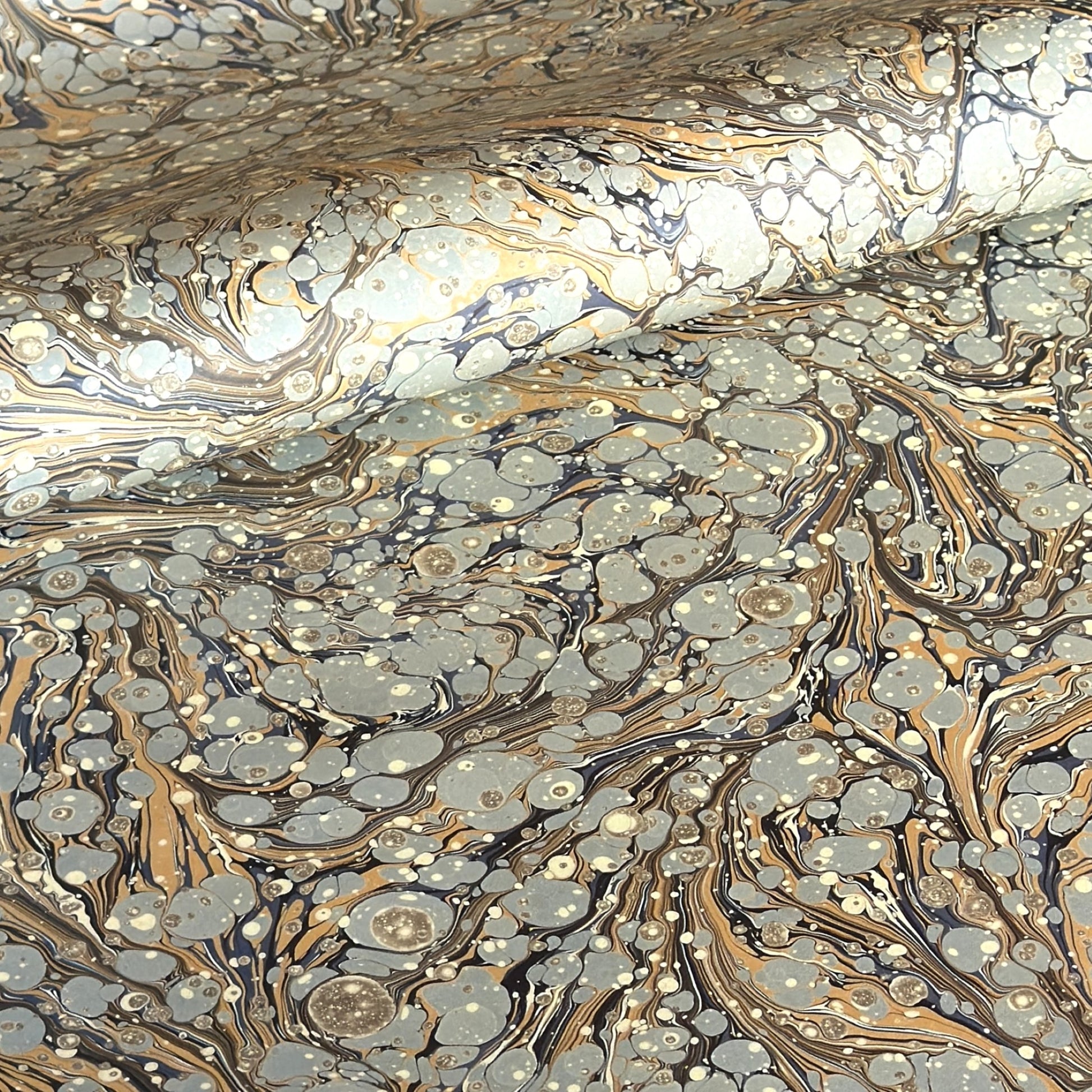 Printed marbled wrapping paper by Jemma Lewis Marbling. Marbled paper in earth tones of brown, sand, grey and soft blue.