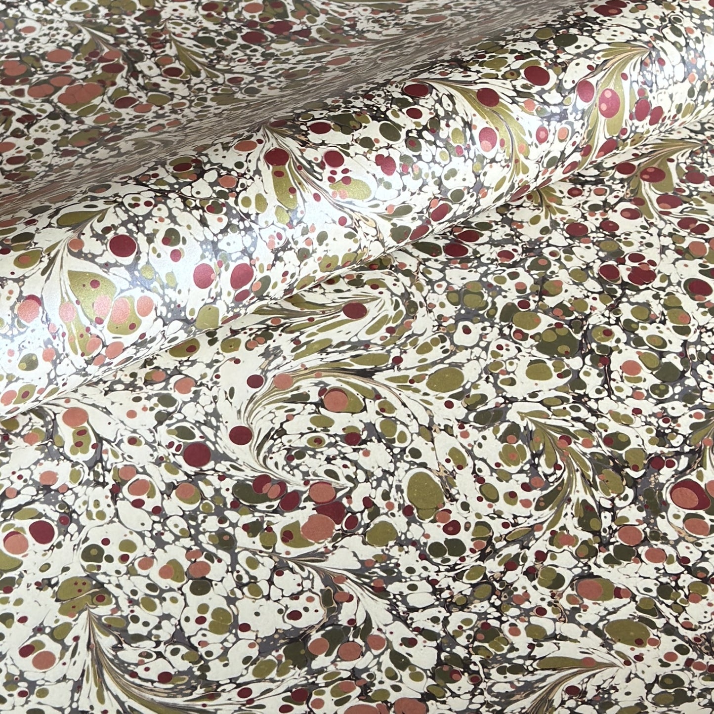 Printed marbled wrapping paper by Jemma Lewis Marbling. Marbled paper with a shimmery base paper and marbled pattern in burgundy, green and white. 