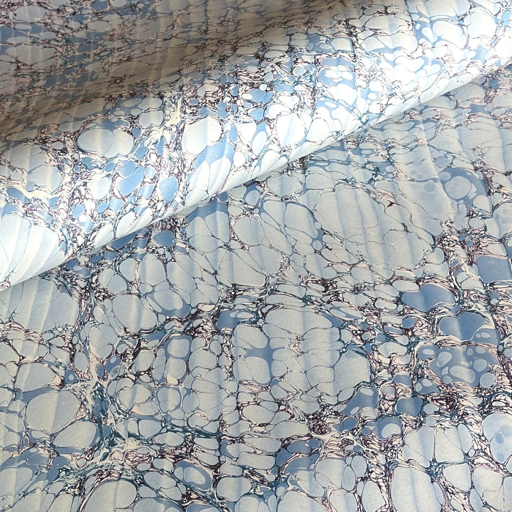 sheet of printed marbled wrapping paper by Jemma Lewis, stone effect in tones of pale blue