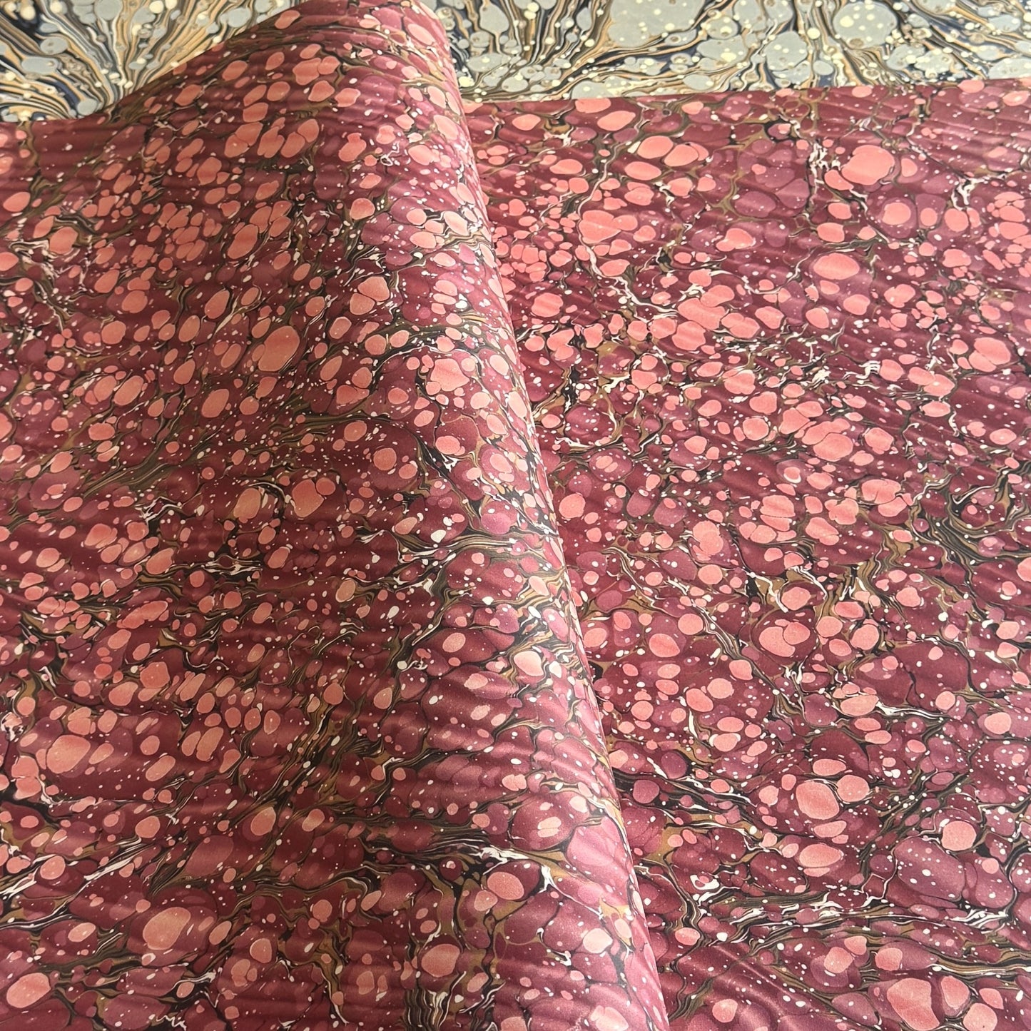 Printed marbled wrapping paper by Jemma Lewis Marbling. Marbled paper in deep burgundy, pinks and brown