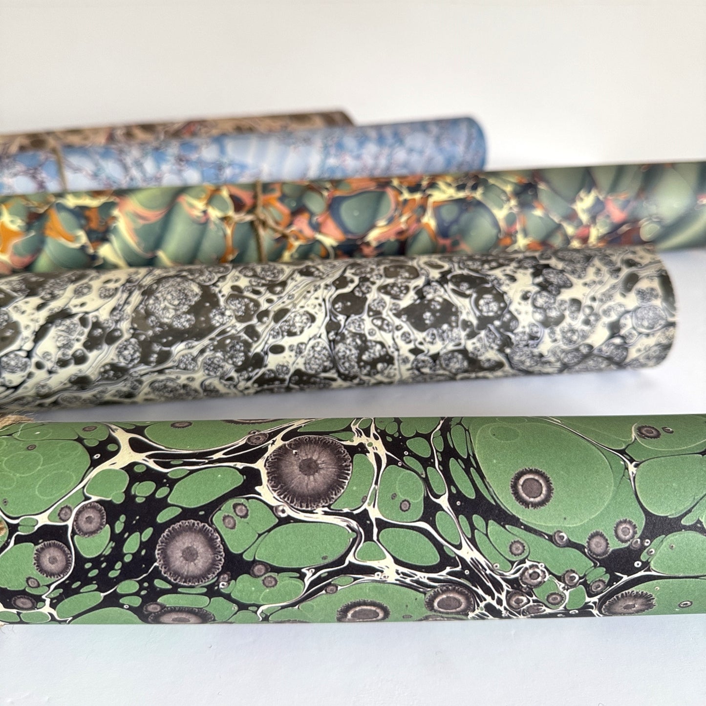 sheet of printed marbled wrapping paper by Jemma Lewis, stone effect in green and grey. Pictured rolled