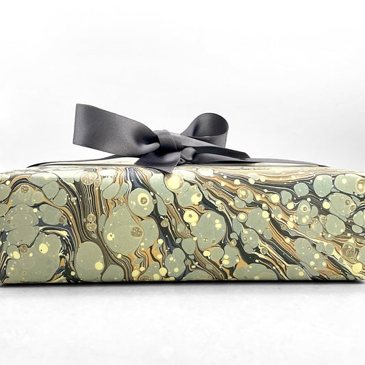 Printed marbled wrapping paper by Jemma Lewis Marbling. Marbled paper in earth tones of brown, sand, grey and soft blue. Pictured wrapped with a grey bow