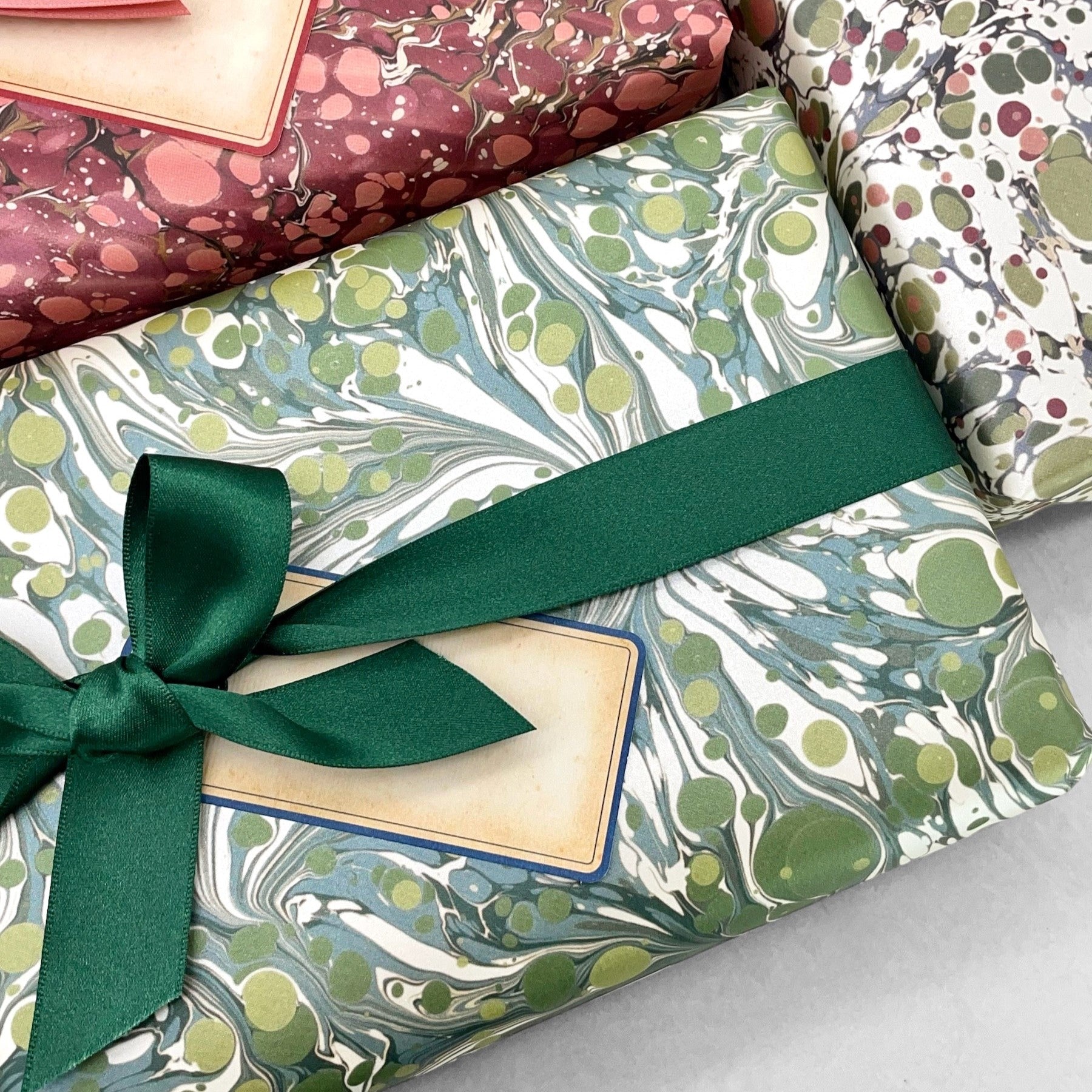 Printed marbled wrapping paper by Jemma Lewis Marbling. Marbled paper with a shimmery base paper and marbled pattern in green, lime and white. Pictured with other marbled presents