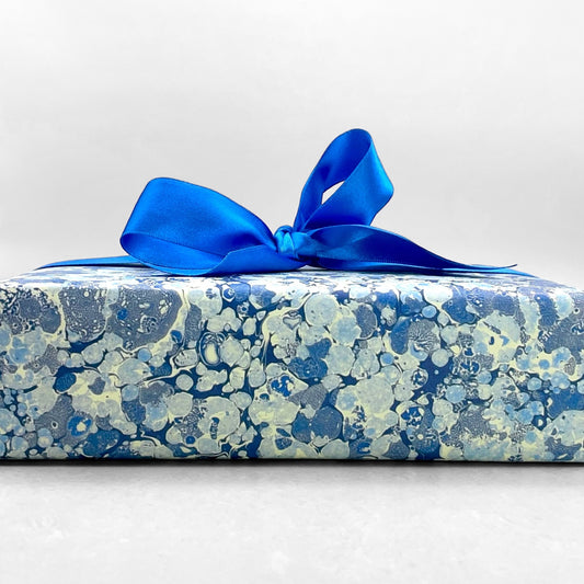 Printed marbled wrapping paper by Jemma Lewis Marbling. Marbled paper in blue and white. Pictured wrapped with a blue bow