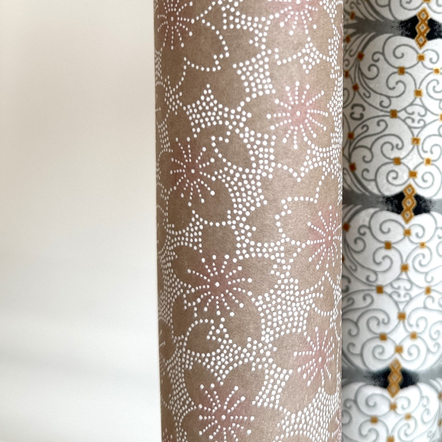 Japanese silkscreen chiyogami paper with a repeat pattern of cherry blossom flowers in taupe and white, close up