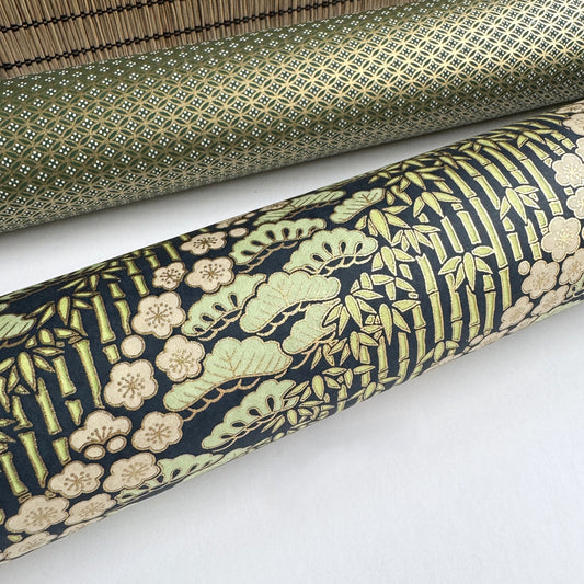a sheet of Japanese silkscreen printed chiyogami paper with a design of trees, bamboo and plum blossom in a palette of mint green, white and dark indigo. Close up