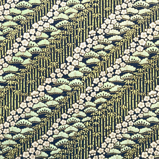 a sheet of Japanese silkscreen printed chiyogami paper with a design of trees, bamboo and plum blossom in a palette of mint green, white and dark indigo