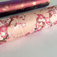 Diagonal branches of pink plum (ume) blossom on a light pink background with gold accents. Japanese chiyogami paper