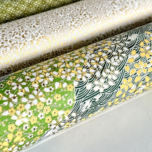 Japanese silkscreen chiyogami paper with a pattern of dark green rivers and grass green banks with an abundance of little flowers in white and yellow. Close up