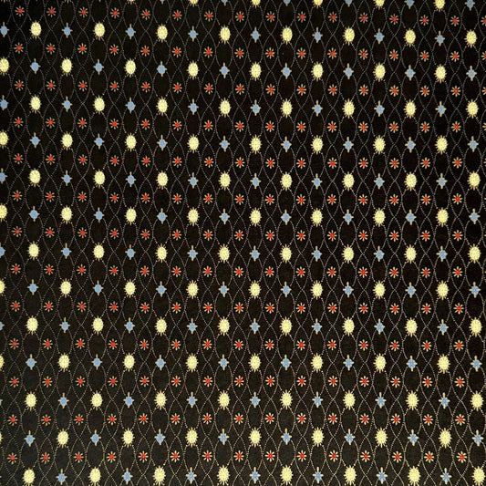 Japanese silkscreen chiyogami paper with a pattern of small repeat motifs in red, blue, lemon and gold on a black background