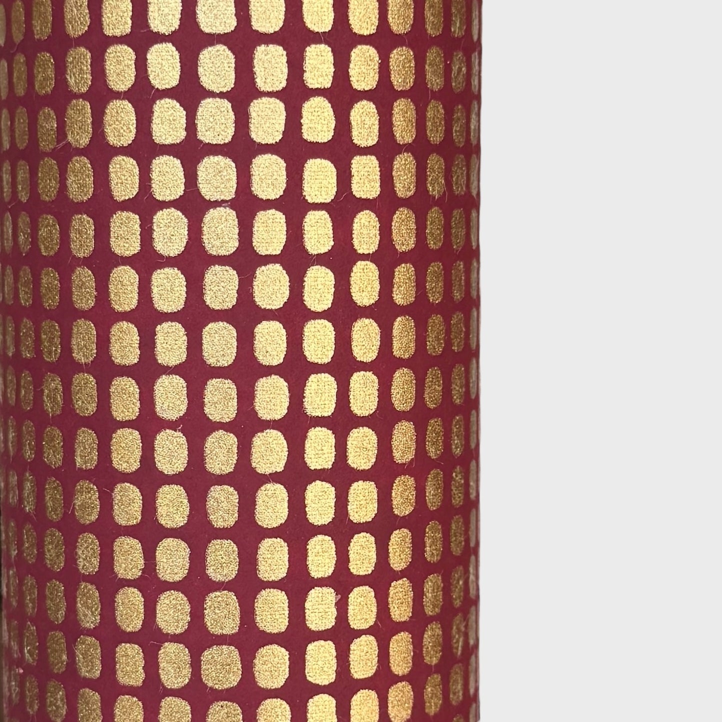 a sheet of Japanese chiyogami paper in rich claret red with a repeat pattern of gold rounded rectangles