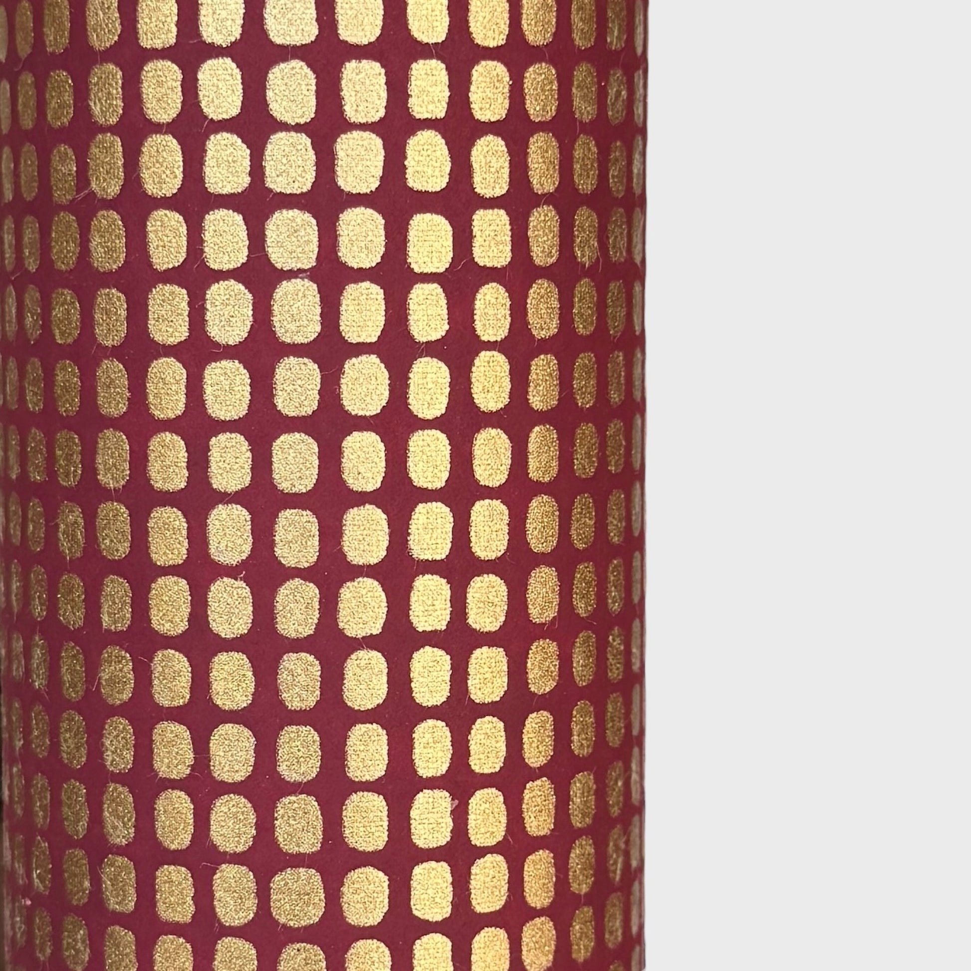 a sheet of Japanese chiyogami paper in rich claret red with a repeat pattern of gold rounded rectangles