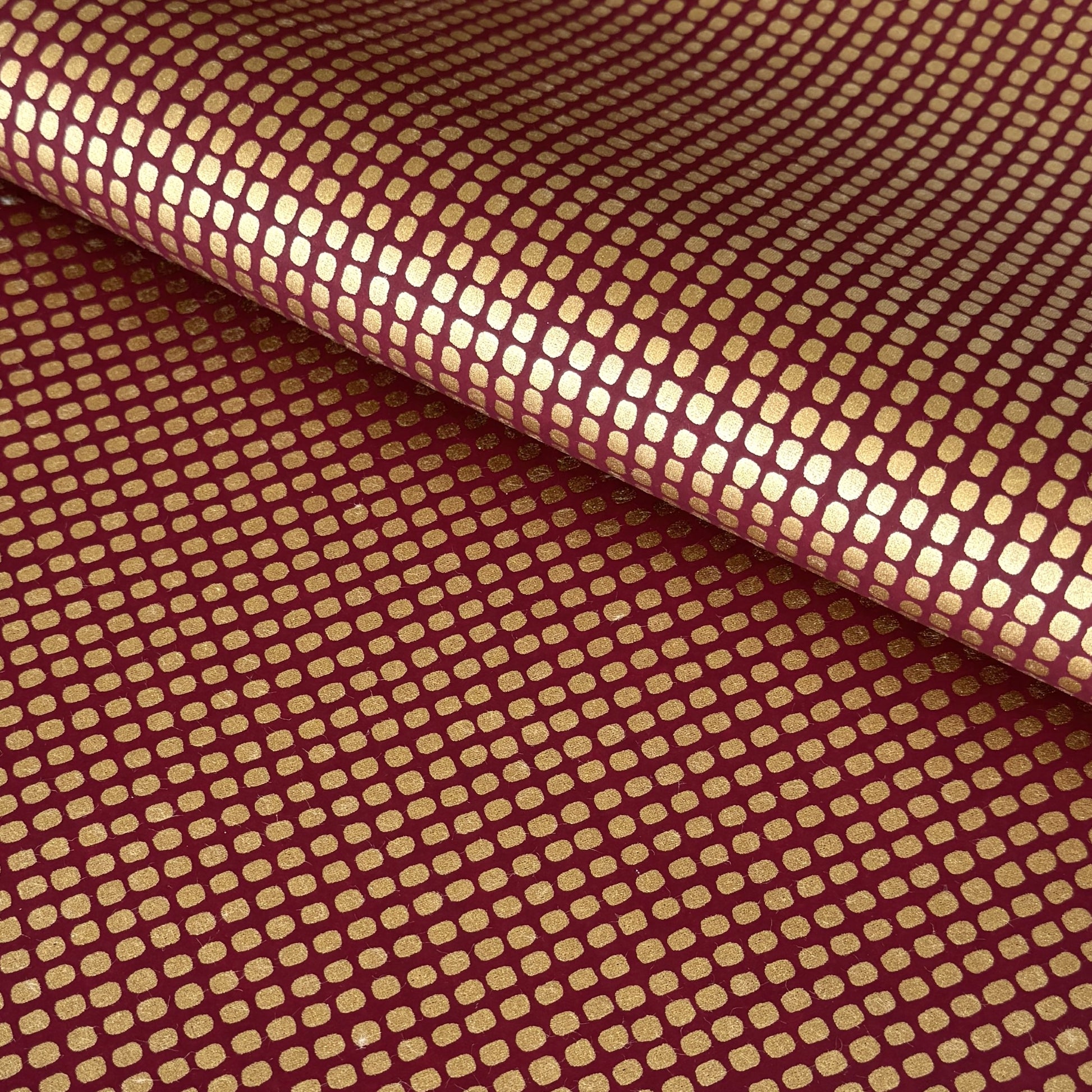 a sheet of Japanese chiyogami paper in rich claret red with a repeat pattern of gold rounded rectangles