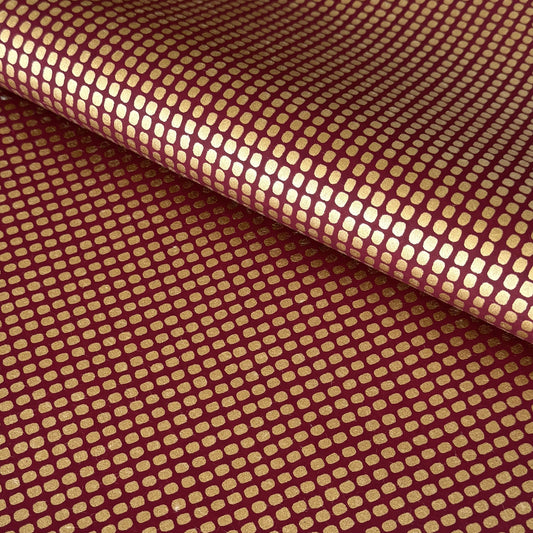 a sheet of Japanese chiyogami paper in rich claret red with a repeat pattern of gold rounded rectangles