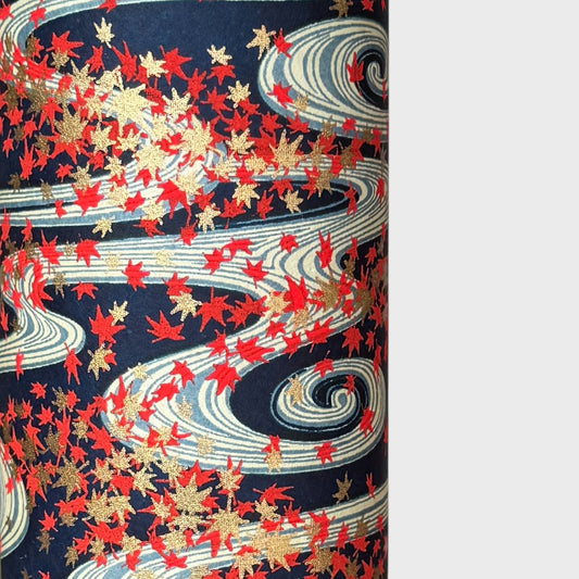 a sheet of Japanese chiyogami paper with a pattern of swirling streams with red and gold falling leaves, dark blue background
