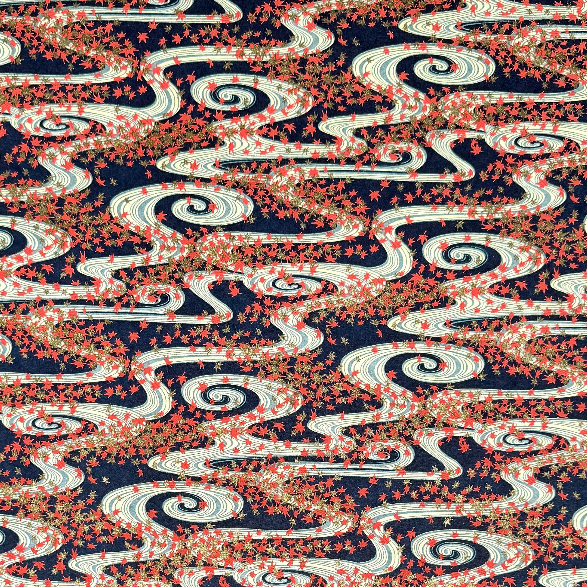 a sheet of Japanese chiyogami paper with a pattern of swirling streams with red and gold falling leaves, dark blue background