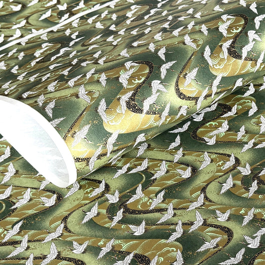 a sheet of Japanese chiyogami paper with white cranes flying on a dark green and gold swirl background