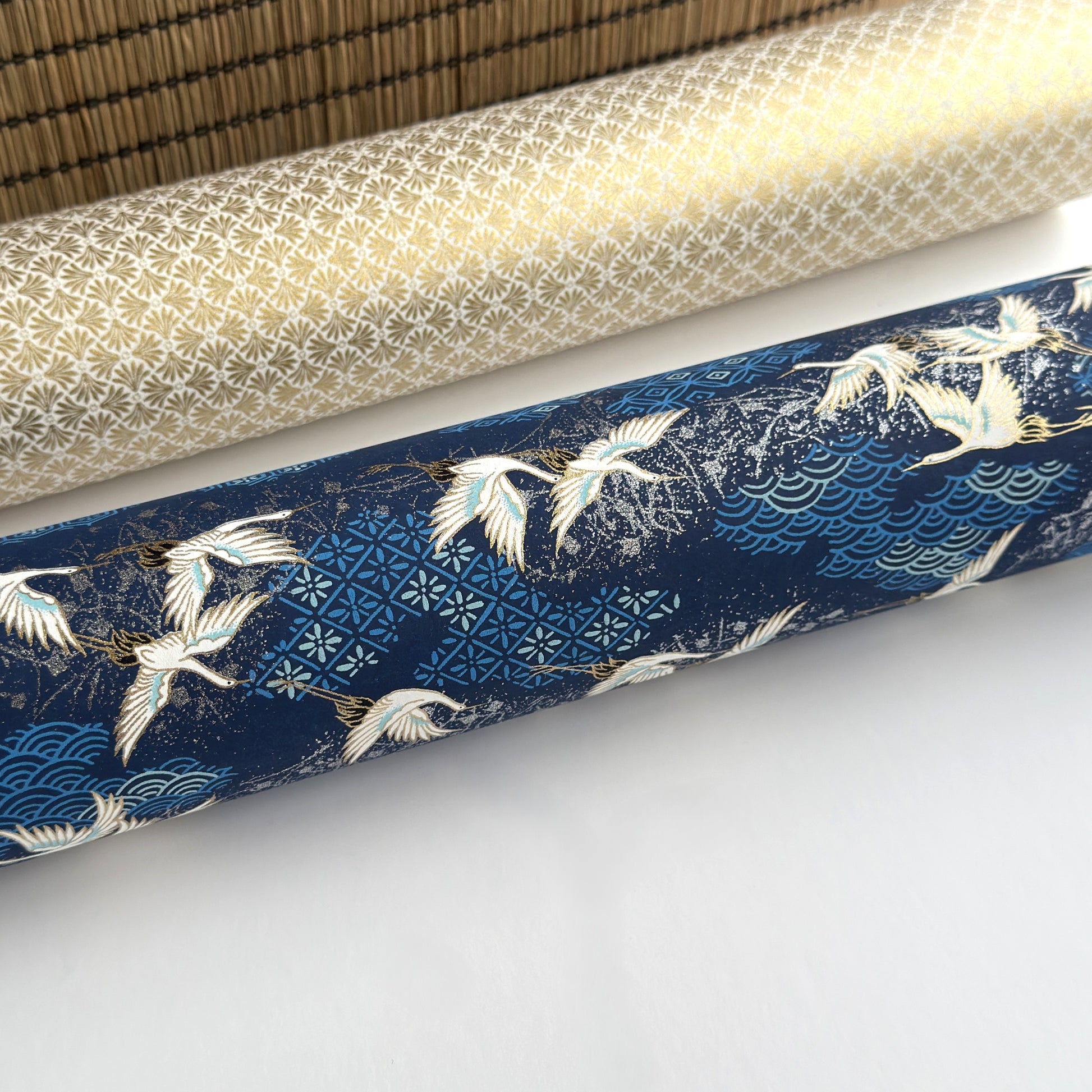 a sheet of Japanese chiyogami yuzen paper with a traditional pattern of white cranes flying with a deep blue background of patterned clouds