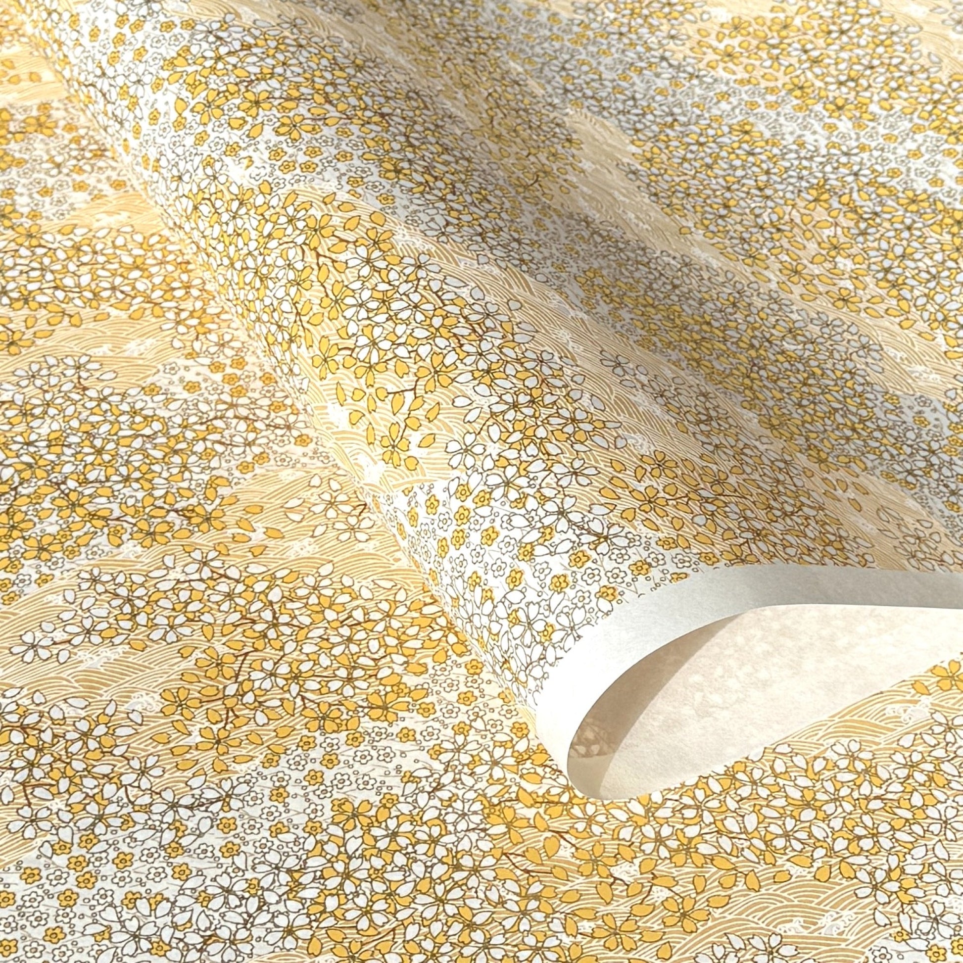 a sheet of Japanese chiyogami yuzen paper with a delicate pattern of little sakura cherry blossom in amber yellow and white