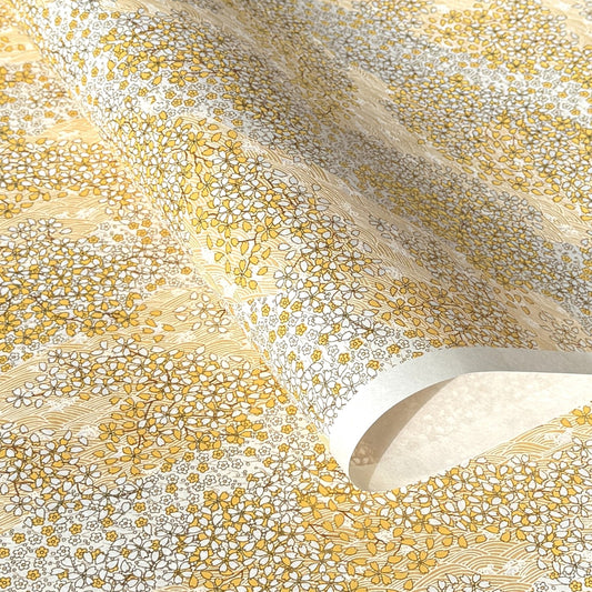 a sheet of Japanese chiyogami yuzen paper with a delicate pattern of little sakura cherry blossom in amber yellow and white