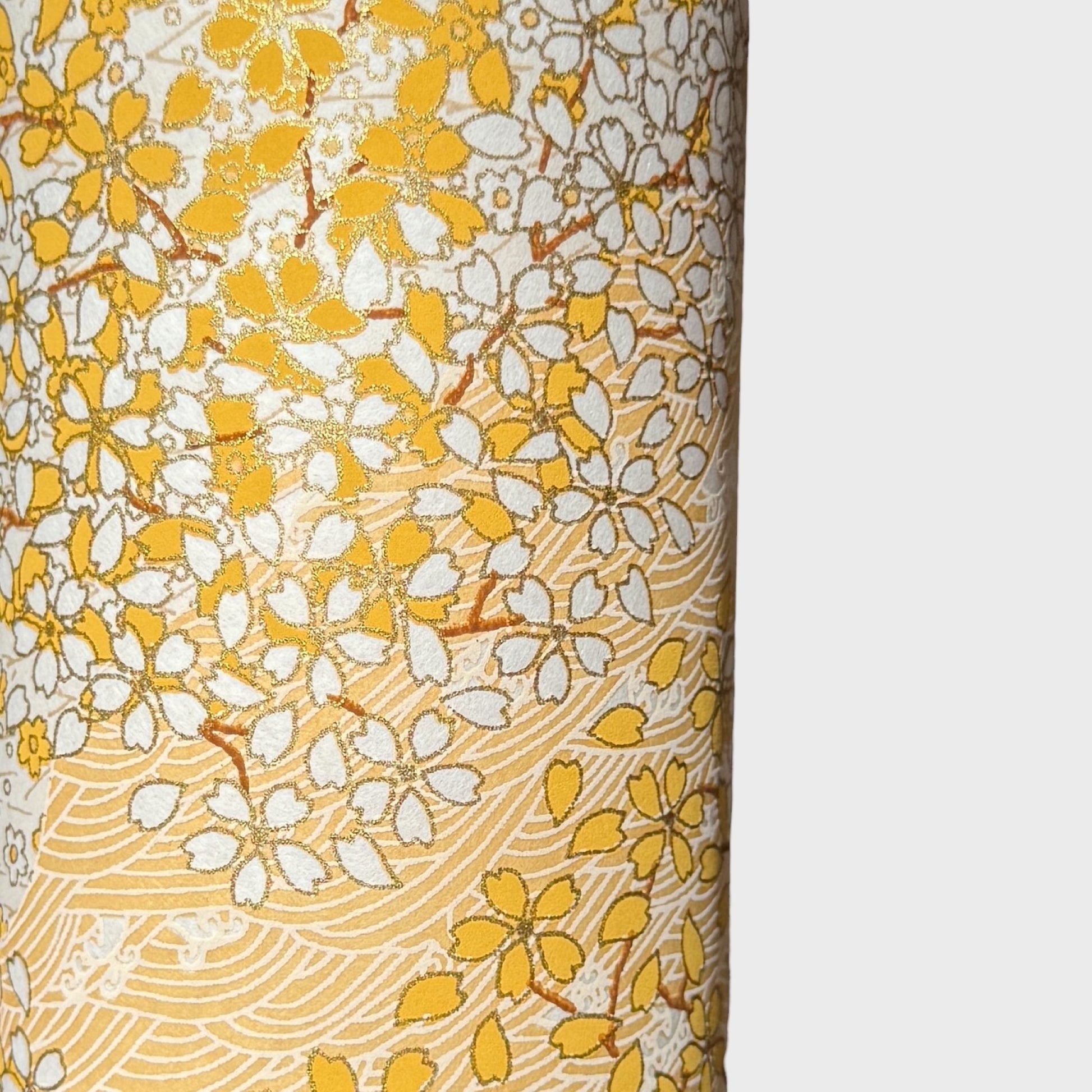 a sheet of Japanese chiyogami yuzen paper with a delicate pattern of little sakura cherry blossom in amber yellow and white