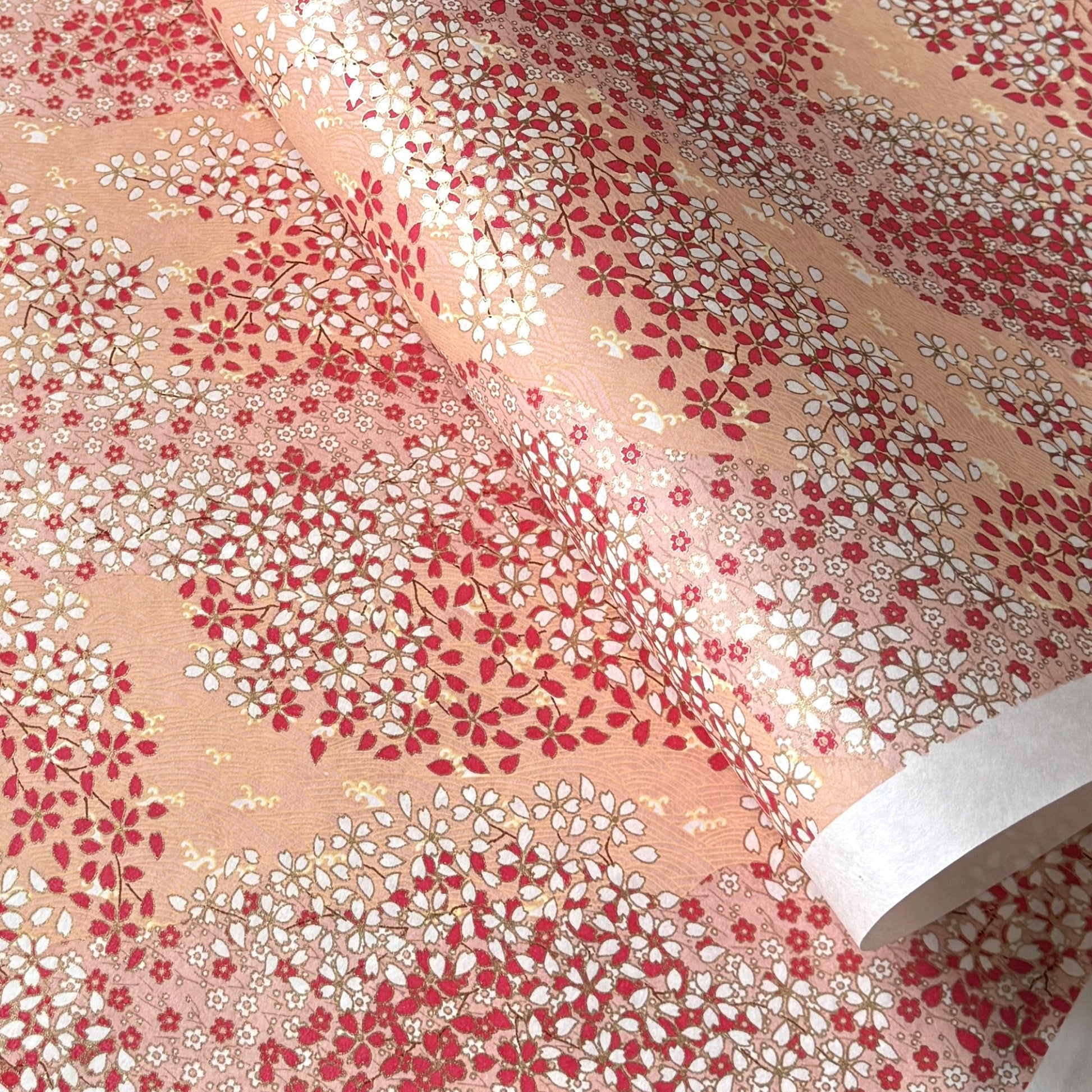 a sheet of Japanese chiyogami paper with a small floral pattern of sakura blossom in shades of pink and white
